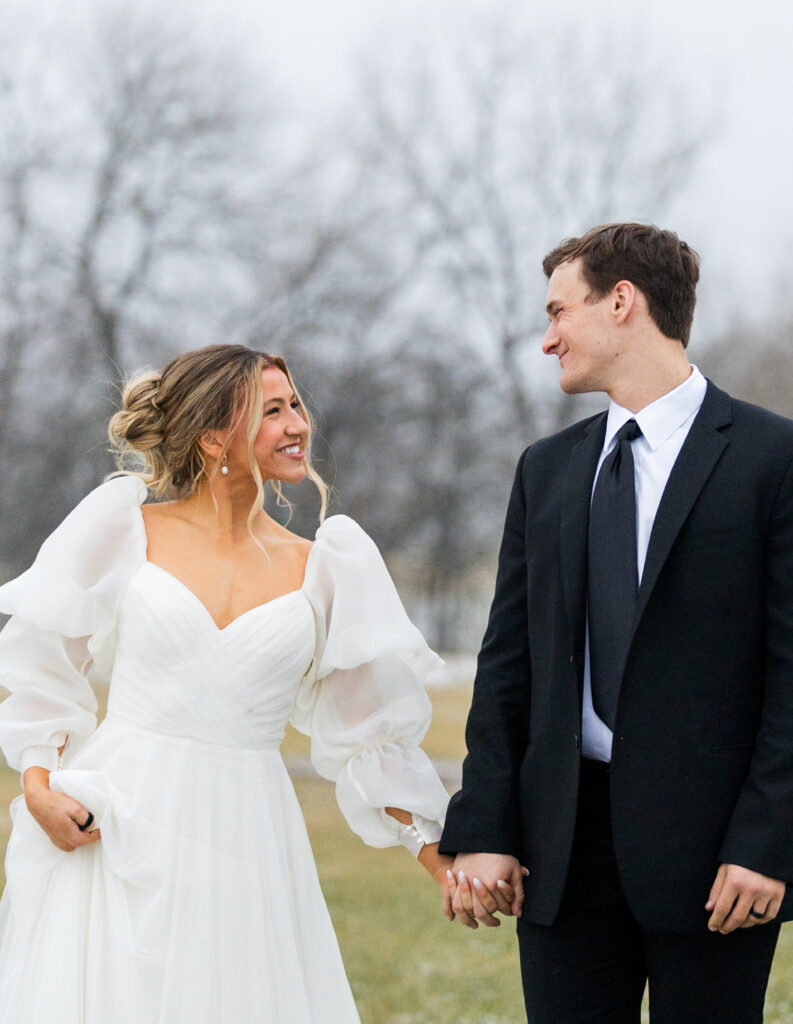 bride and groom in snowy field on their wedding day